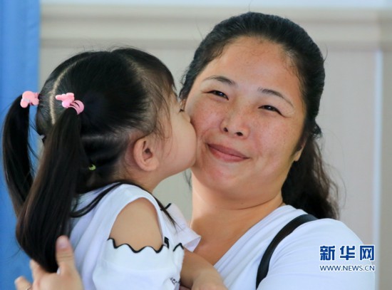 在亲子游戏中,一名小女孩开心地亲吻妈妈的脸.新华网 肖和勇 摄